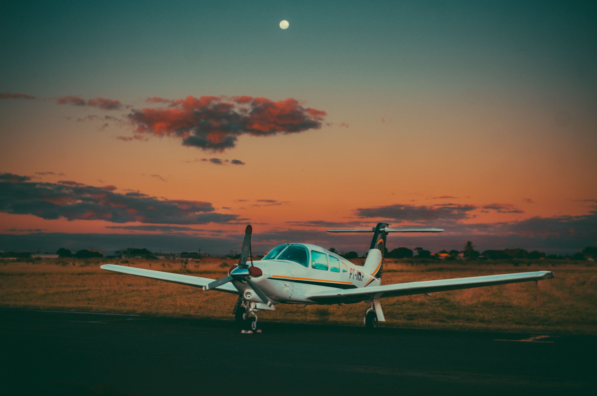 Piper aircraft parked at sunset under an orange sky